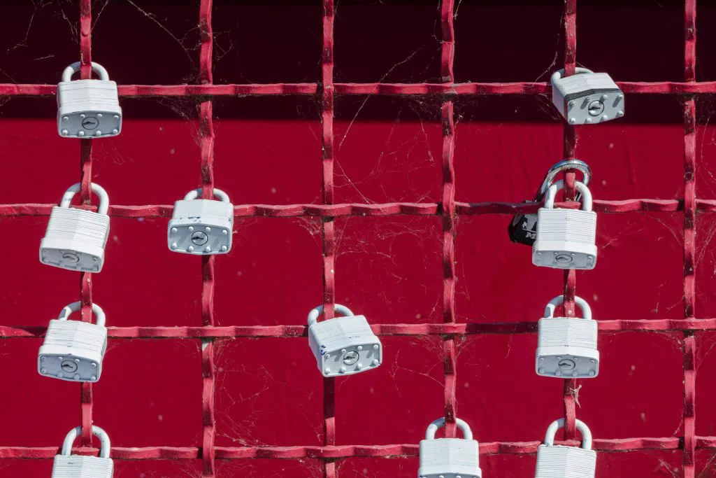picture of padlocks hanging on fence with red background