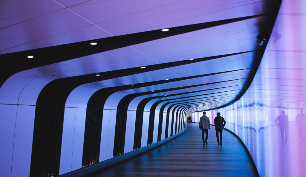 two people walking down a blue lit hallway